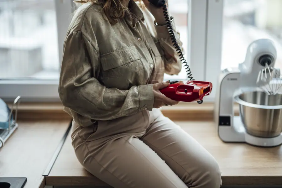 Woman holds red kitchen device while talking on phone