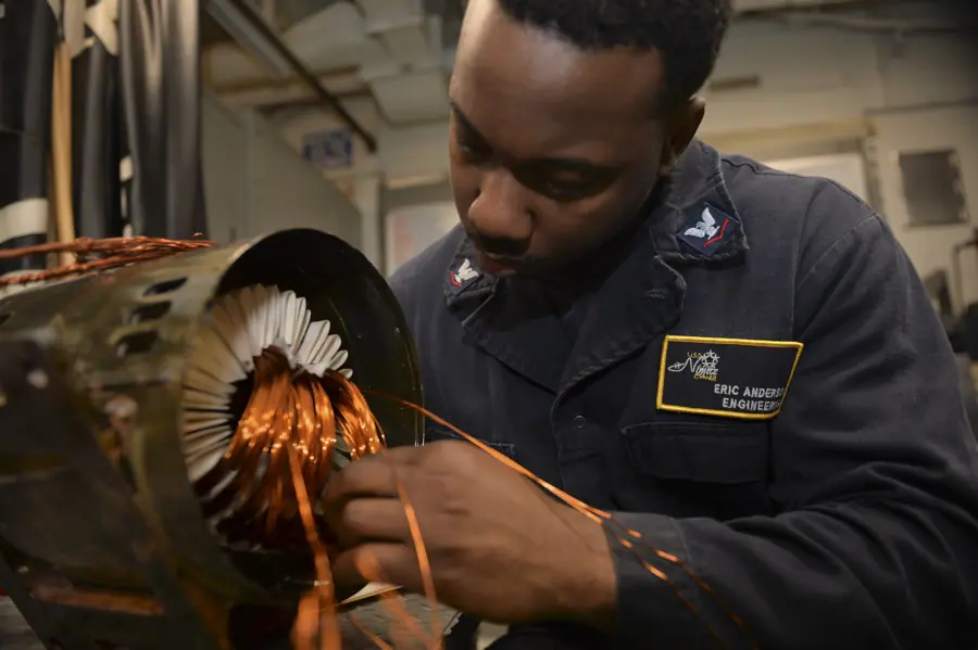 Electrician's Mate 3rd Class Eric Anderson rewiring the coils of a motor