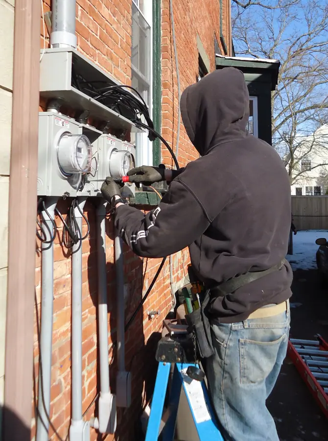 Electrician using screwdriver to install external panels for meters in NJ