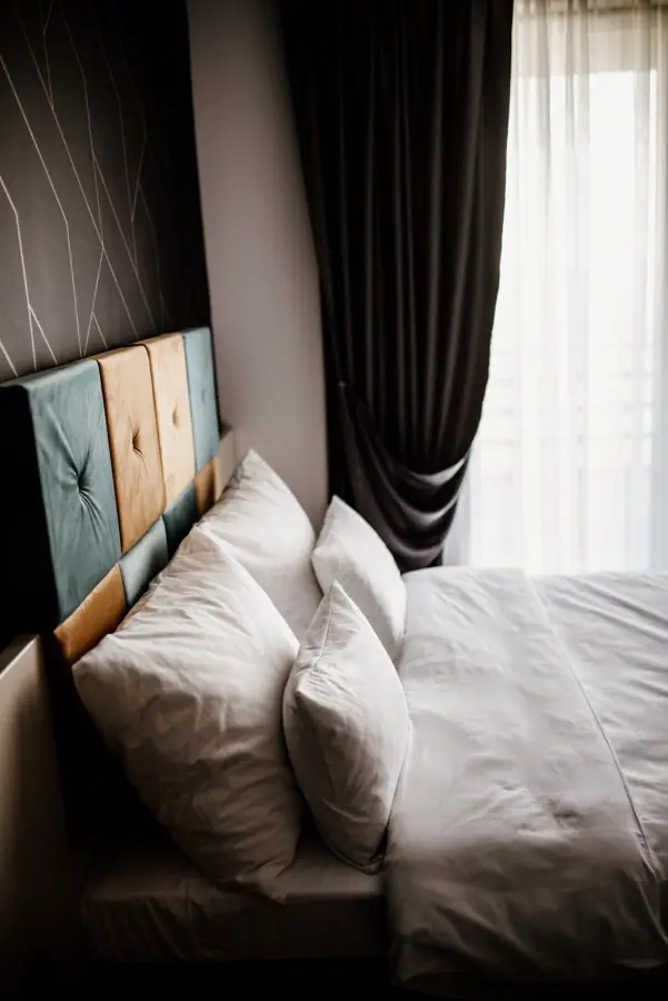 Cozy modern bedroom with plush pillows and elegant drapes in bright daylight