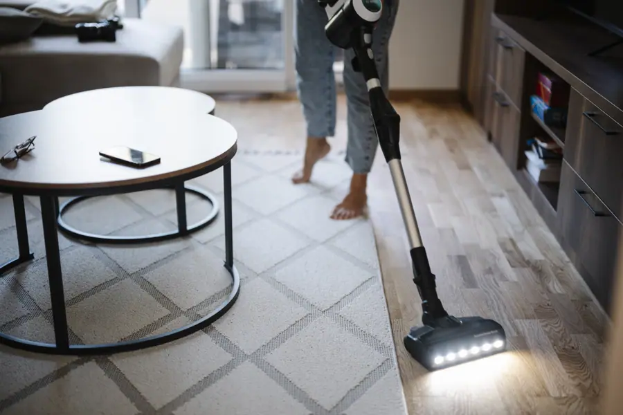 Person cleaning living room floor with vacuum cleaner in modern home