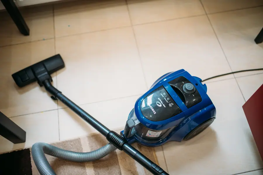 Vacuum cleaner placed on tiled floor with cleaning tools ready for use in a modern living room setting during daytime