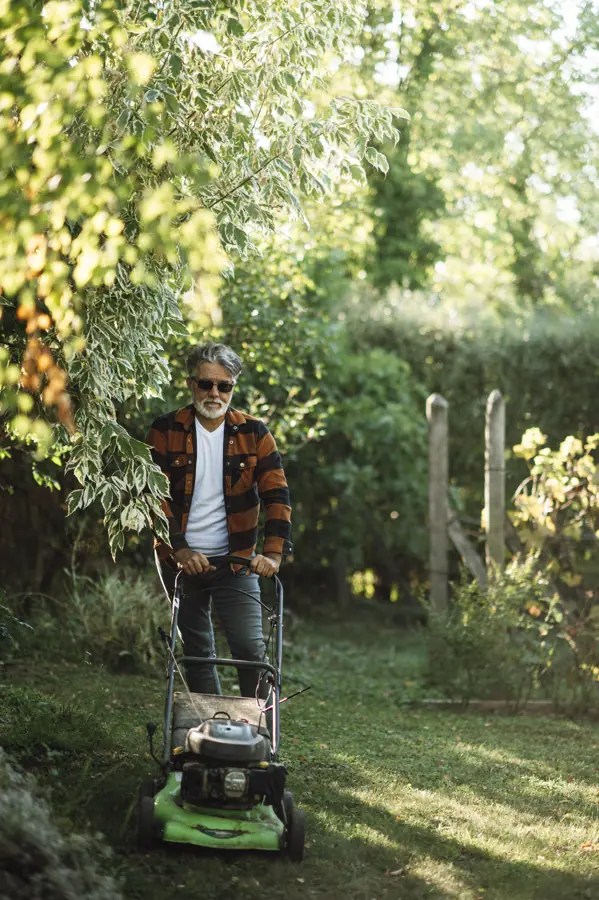 Man mowing lawn in a lush garden