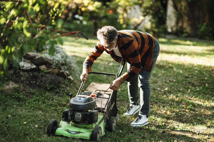 Man prepares to mow the lawn in a backyard