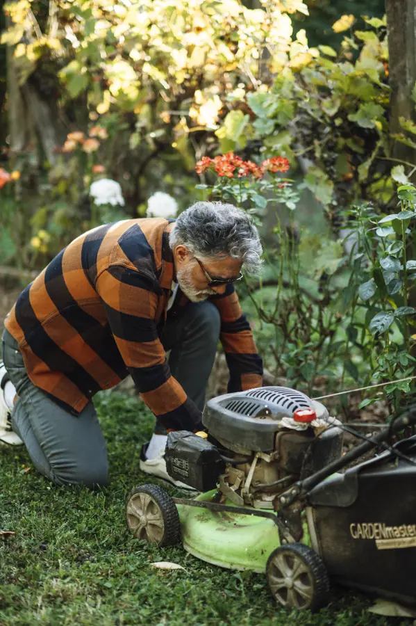 Man repairs lawn mower in garden