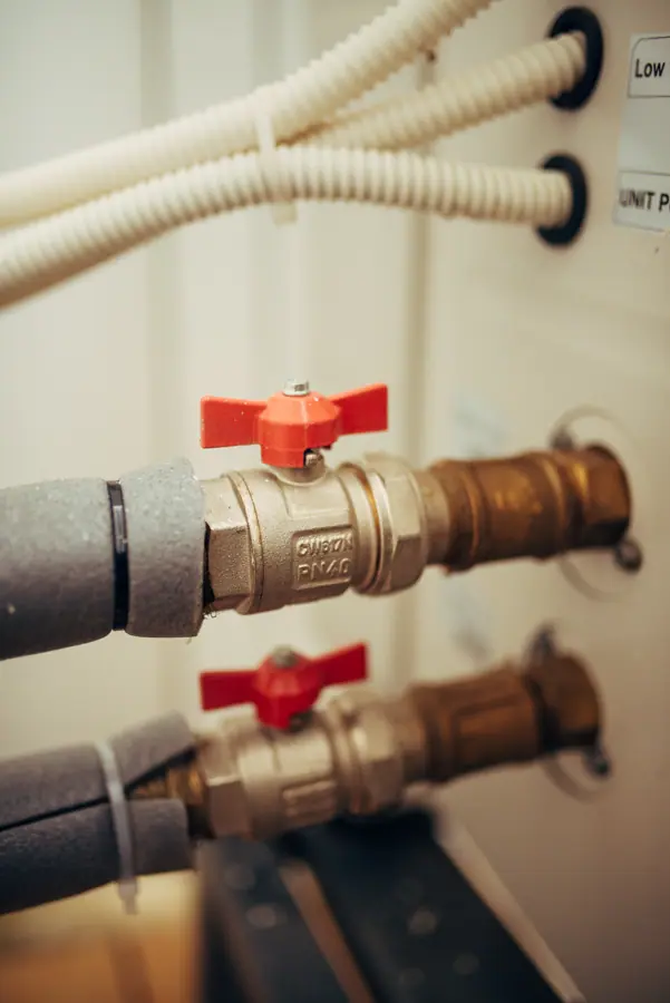 Close-up of brass plumbing valves with red handles in a home installation