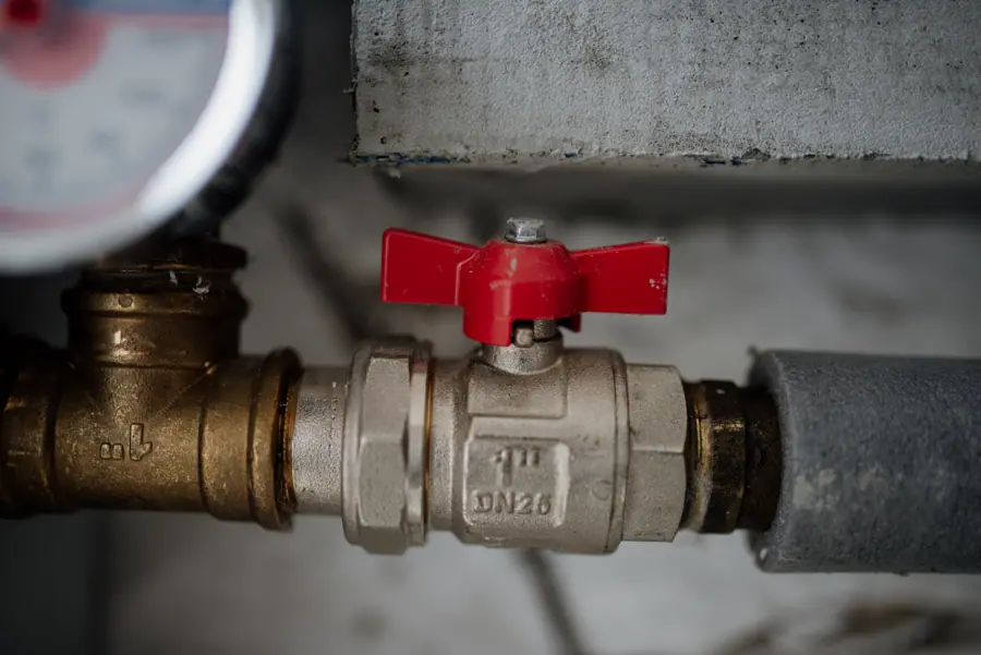 Close-up view of a red valve on a metallic pipe system with a pressure gauge in an industrial setting