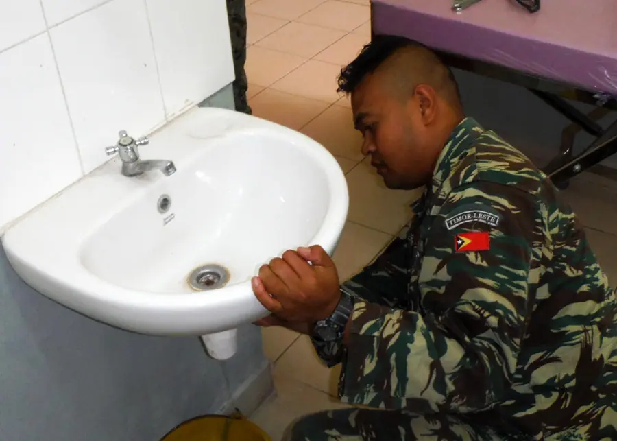 Soldier repairs a leaky sink at the Manatuto Maternity Clinic