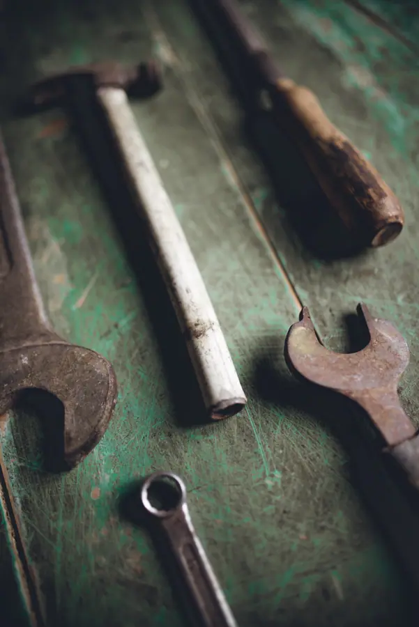 Rustic tools spread across a weathered wooden workbench showcasing craftsmanship and utility