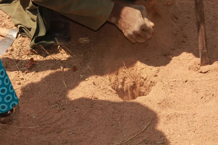 A man drilling a hole to pitch his retailing tent