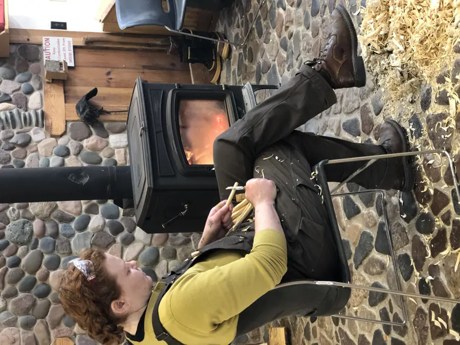 A Woodworker Whittling in Front of a Wood Stove